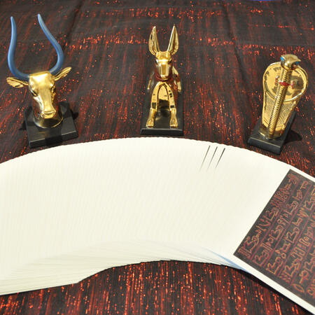 A fanned tarot deck and three golden statues of Egyptian Gods
